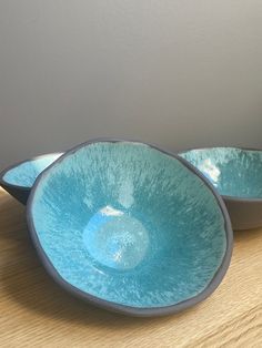 two blue bowls sitting on top of a wooden table