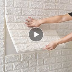 a person is placing something on top of a brick wall with their hands and thumbnails