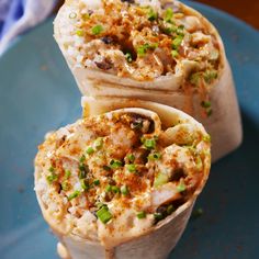 two burritos are sitting on a blue plate with green onions and seasoning