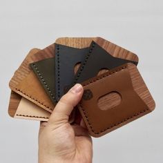 a hand holding four leather wallets in different colors