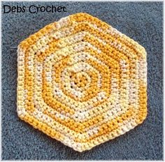 a yellow and white crocheted dishcloth on a blue carpet with the words debs crochet written below it