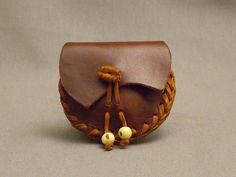 a small brown leather purse with two beads on it's side and one bead in the middle