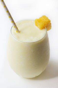 a glass filled with milk and a straw sticking out of it's top, sitting on a white surface