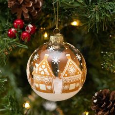 an ornament hanging from a christmas tree decorated with gingerbread houses and snowflakes