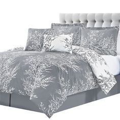 a bed with grey and white comforters and pillows