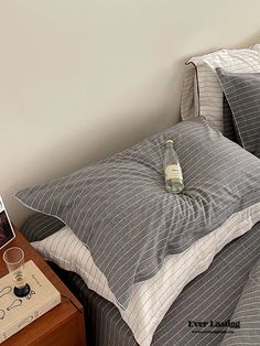 a bottle of water sitting on top of a bed next to pillows and a night stand