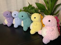 four small stuffed animals sitting on top of a table next to a potted plant