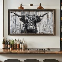 a cow painting hanging on the wall above a bar with stools in front of it