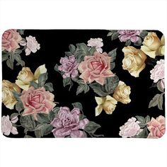 a black area rug with pink and yellow roses on the front, and green leaves on the back