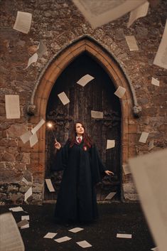 a woman standing in front of a door with papers flying around her and holding a flashlight