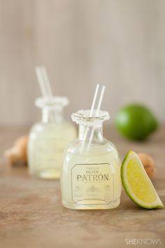 two small bottles filled with liquid next to limes