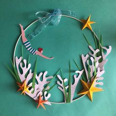 a wreath made out of paper with seaweed and starfishs on the sides