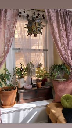 some plants are sitting on a window sill in front of a curtained window