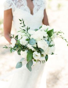 a bride holding a bouquet of white flowers