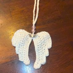 crocheted angel ornament on wooden table with string and beaded cord