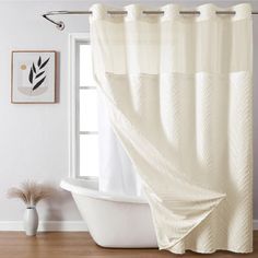 a bath tub sitting next to a window covered in a white shower curtain and matching rug