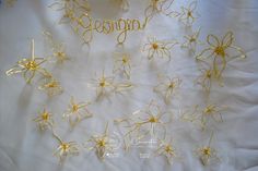 gold wire flowers with the word sequin written in cursive writing on a white sheet