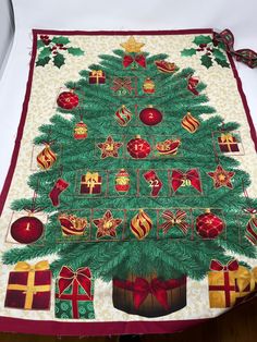 a christmas tree quilted on top of a table with presents around it and ribbons