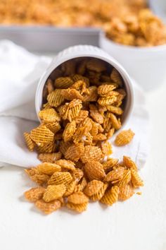 a white bowl filled with corn flakes on top of a table next to a pan of food