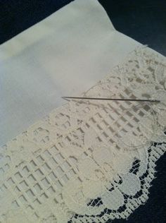 a pair of scissors cutting fabric on top of a piece of white paper with crochet lace