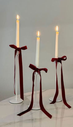 three white candles with red ribbon tied around them