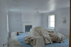 an empty room is being painted white and covered with cloths in preparation for painting