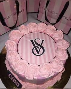 there is a pink cake with roses on it and two bags behind it that say victoria's crest