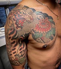 a man with a tiger tattoo on his arm and chest is standing in front of a window