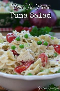 a white bowl filled with pasta salad on top of a wooden table