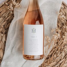 a bottle of wine sitting on top of a table next to some dried grass and flowers