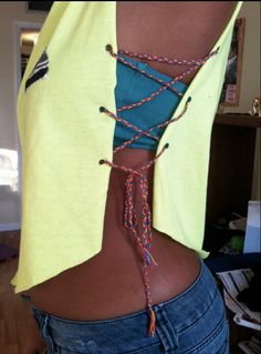 a woman wearing a yellow shirt and blue jeans with an orange string tied around her waist