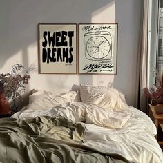 two posters on the wall above a bed in a room with white sheets and pillows