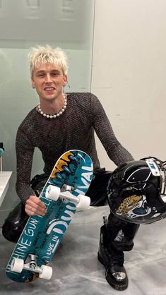 a man sitting on the ground holding a skateboard