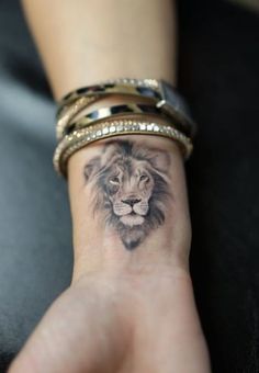 a woman's wrist with a lion tattoo on it