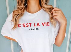 The unisex C'est La Vie - France shirt in its minimal design shows classy style on a trip to France. It would also be a great gift for a French teacher! Wear it on a casual beach day, or combine it with jeans and a jacket for a city trip. Should you love it in another color, just give me a shout and I am happy to offer it in a color of your choice. ♥PRODUCTION TIME: 1-5 days (usually 2-3 days) ♥SHIPPING TIME: 3-5 days ♥PRODUCT DESCRIPTION: Comfort Colors Unisex T-shirt Super soft cotton and exce Custom Text T-shirt With Relaxed Fit For Summer, Custom Text Relaxed Fit T-shirt For Summer, Summer Relaxed Fit T-shirt With Custom Text, Custom Text Crew Neck T-shirt For Summer, Teacher Wear, Trip To France, Travel Tees, French Teacher, Classy Style