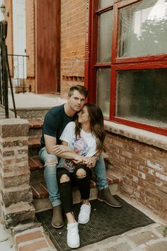 a man and woman are sitting on the steps together, smiling at each other as they hug