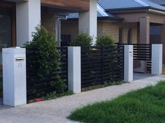 a black and white fence is in front of a house with grass on the sidewalk