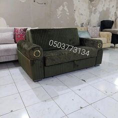 a green couch sitting on top of a white tile floor next to a wall with peeling paint