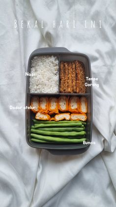 a bento box filled with rice, meat and veggies on top of a bed