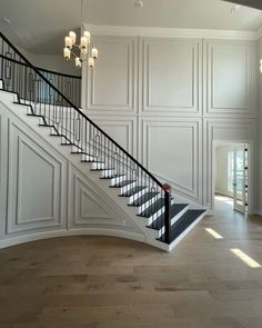 an empty room with white walls and wood flooring, stairs leading up to the second floor