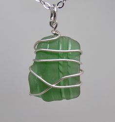 a piece of green sea glass sitting on top of a silver chain