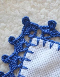 a close up of a piece of cloth with blue thread on it and an embroidered square in the middle