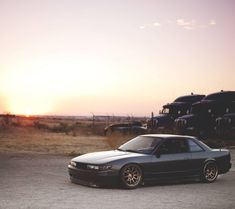 the car is parked on the side of the road in front of some cars at sunset