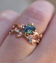 a close up of a person's hand holding a ring with a blue stone