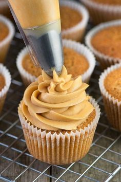 a cupcake being frosted by a piping tool