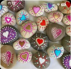 some rocks with hearts painted on them are arranged in a circle and have different colors