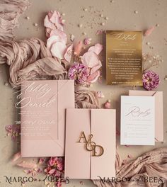 the wedding stationery is laid out with pink flowers and gold foil on it's side