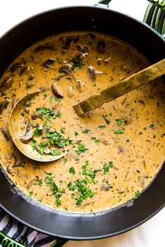 a bowl of soup with mushrooms and parsley on the side, ready to be eaten