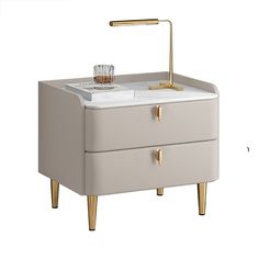 a white and gold bedside table with a glass on the top, next to a brass faucet