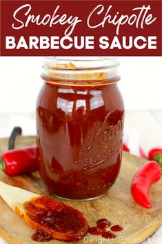 a jar filled with barbecue sauce sitting on top of a cutting board next to peppers